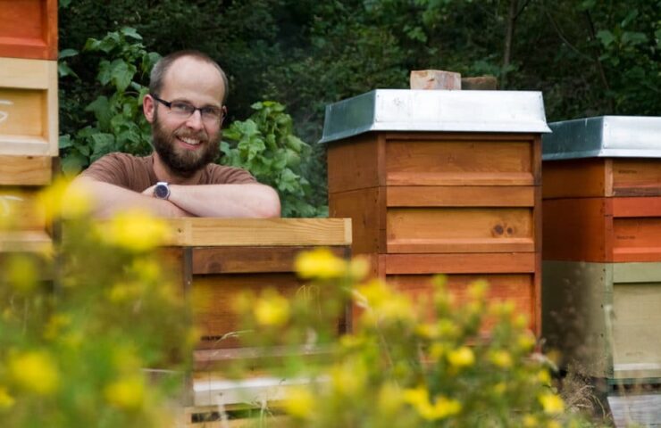 Demeter-Imker Alexander Schlotter lehnt auf einem Bienenstock