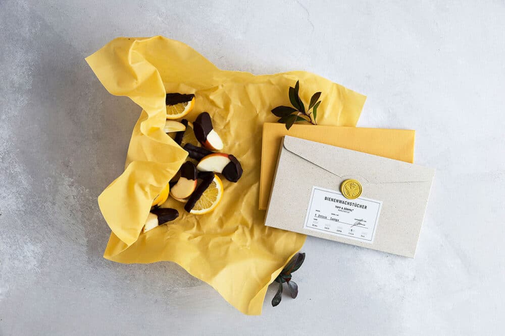 Zwei Bienenwachstücher Large in Gelb mit einer Graspapier-Verpackung